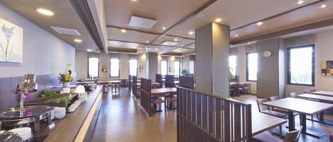 A modern dining area with high tables and booths, a buffet counter, and a clock on the wall.