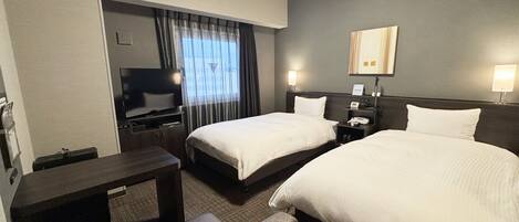 A hotel room with two beds, a TV, a desk, and a chair.