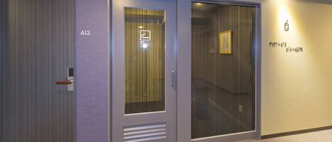 A hotel corridor with doors numbered 613 and 619, featuring a modern design with metallic and glass elements.