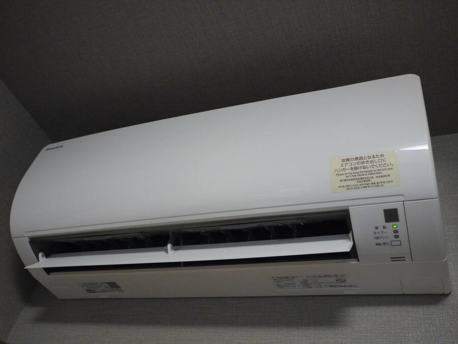 Un equipo de aire acondicionado blanco con un panel de control y una etiqueta de advertencia en un idioma extranjero.