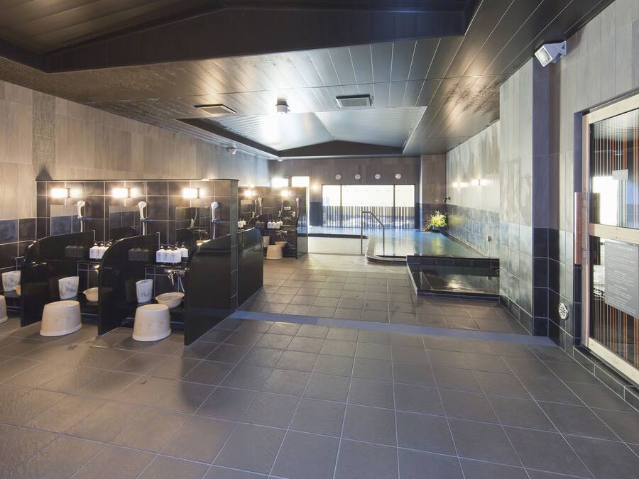 A modern bathroom with multiple sinks, hand dryers, and a large window providing natural light.