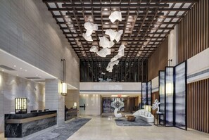 A modern hotel lobby with a reception desk, seating area, and decorative ceiling elements. - Days Hotel by Wyndham Guangzhou Hantian (Guangzhou)