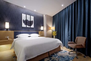 Une chambre d’hôtel moderne avec un grand lit, des lampes de chevet, un bureau et une chaise.