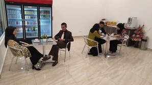 Sala de reuniones con un refrigerador lleno de bebidas, una máquina de café y un arreglo floral.