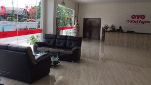Un vestíbulo de hotel con una recepción, un sofá y una mesa de vidrio.