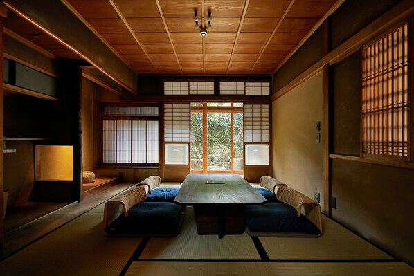 A traditional Japanese room with tatami flooring, a low table, cushions, and sliding shoji doors. - Umeyu No Yado by YADORU KYOTO HANARE (Kyoto)