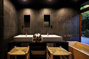 A modern bathroom with two sinks, a large mirror, and a bathtub. There are wicker chairs in front of the sinks. - Umeyu No Yado by YADORU KYOTO HANARE (Kyoto)