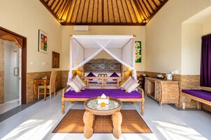 Habitación con cama, mesa y banco. Zona de ducha a la izquierda.