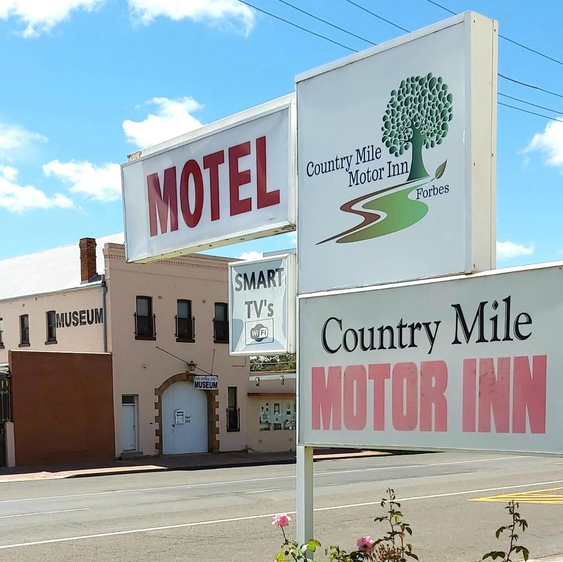 A motel sign with a tree logo and the name 'Country Mile Motor Inn'.
