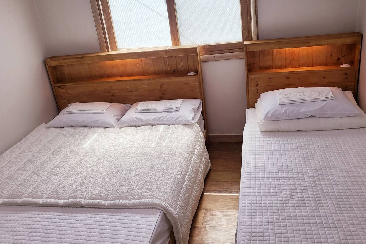 Two single beds with wooden headboards, white bedding, and a window above.