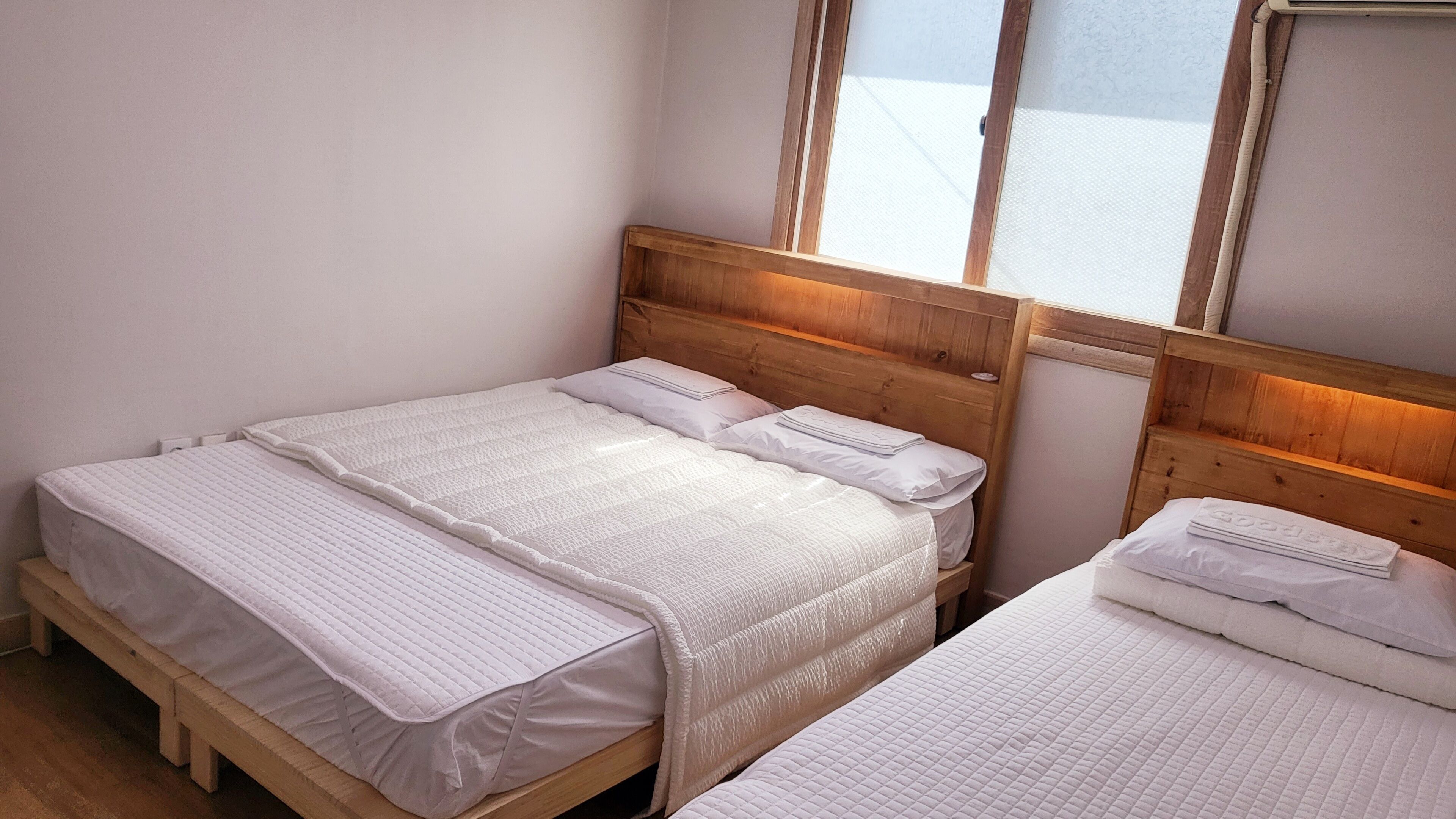 A double bed with a wooden headboard and a window above it.