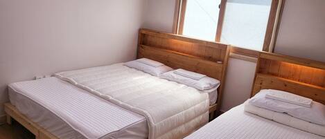 A double bed with a wooden headboard and a window above it.