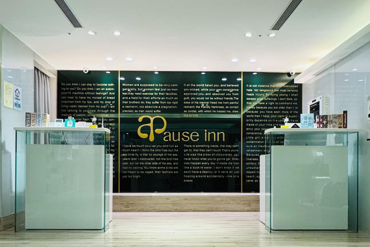 Un espace d’accueil avec un mur noir sur lequel figurent du texte et le logo de « Pause Inn ».