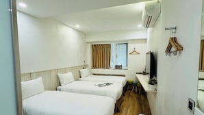 A hotel room with two beds, a desk, a TV, and an air conditioning unit. - APause Inn (Taipei)