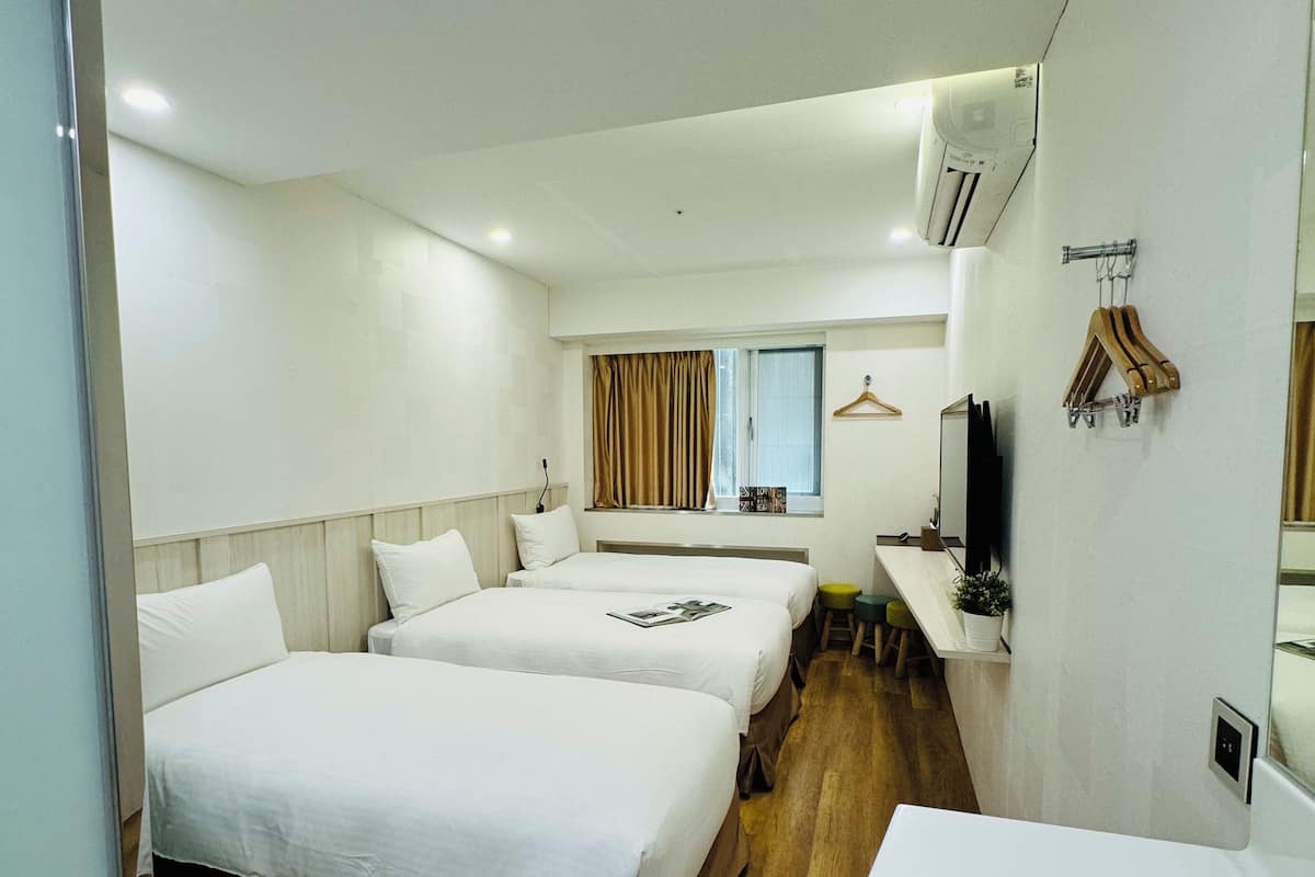 Une chambre d’hôtel avec deux lits, un bureau, une télévision et un appareil de climatisation.