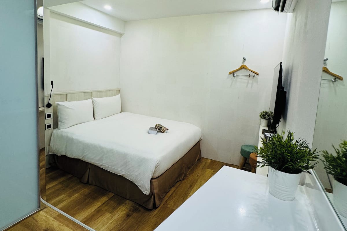 Une chambre à coucher moderne avec un lit, une table de chevet et une plante en pot.