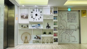 A modern lobby with a wooden floor, a large wall clock, and a subway map. - APause Inn (Taipei)