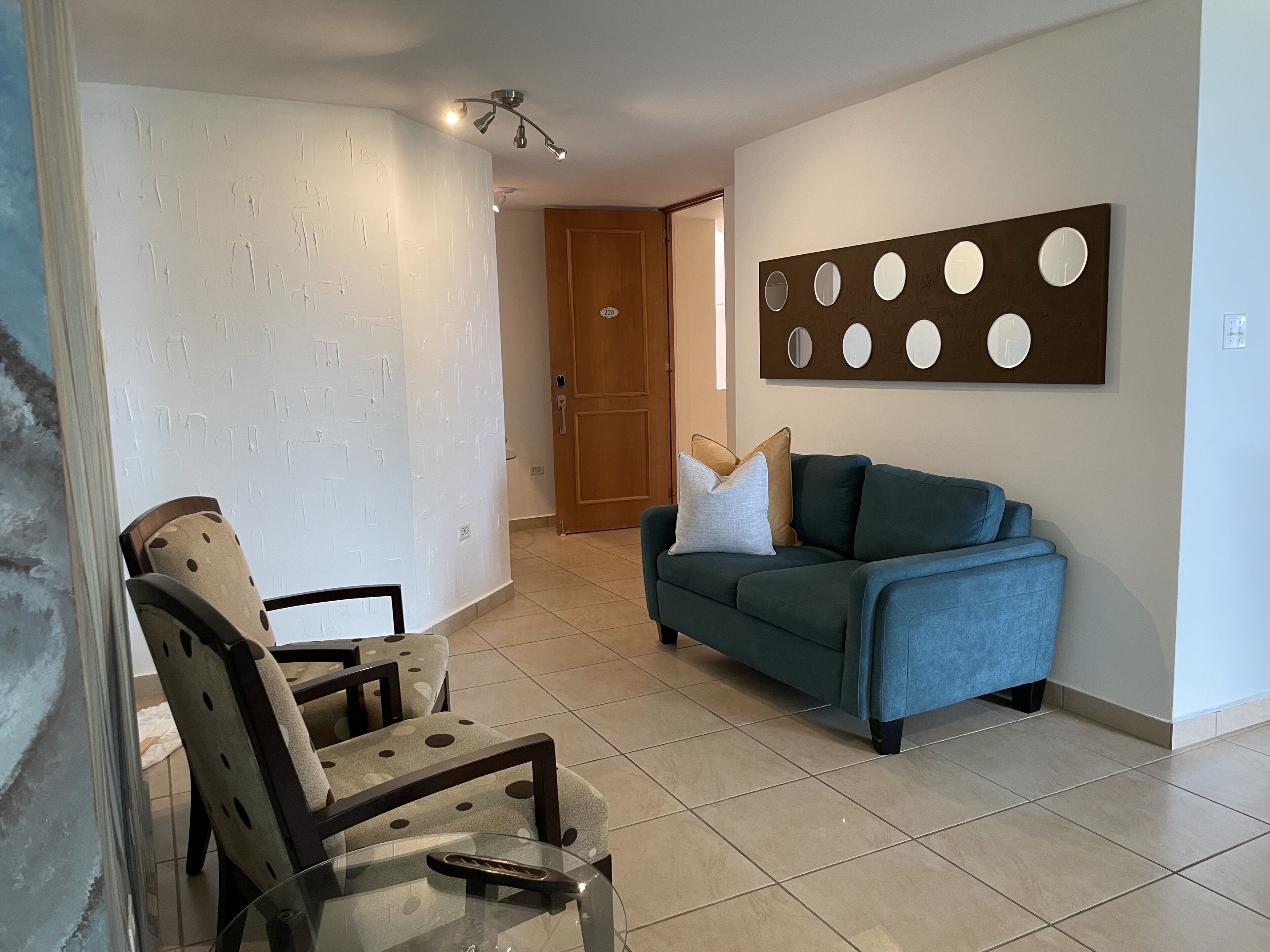 A living room with a sofa, a chair, and a wall-mounted artwork.