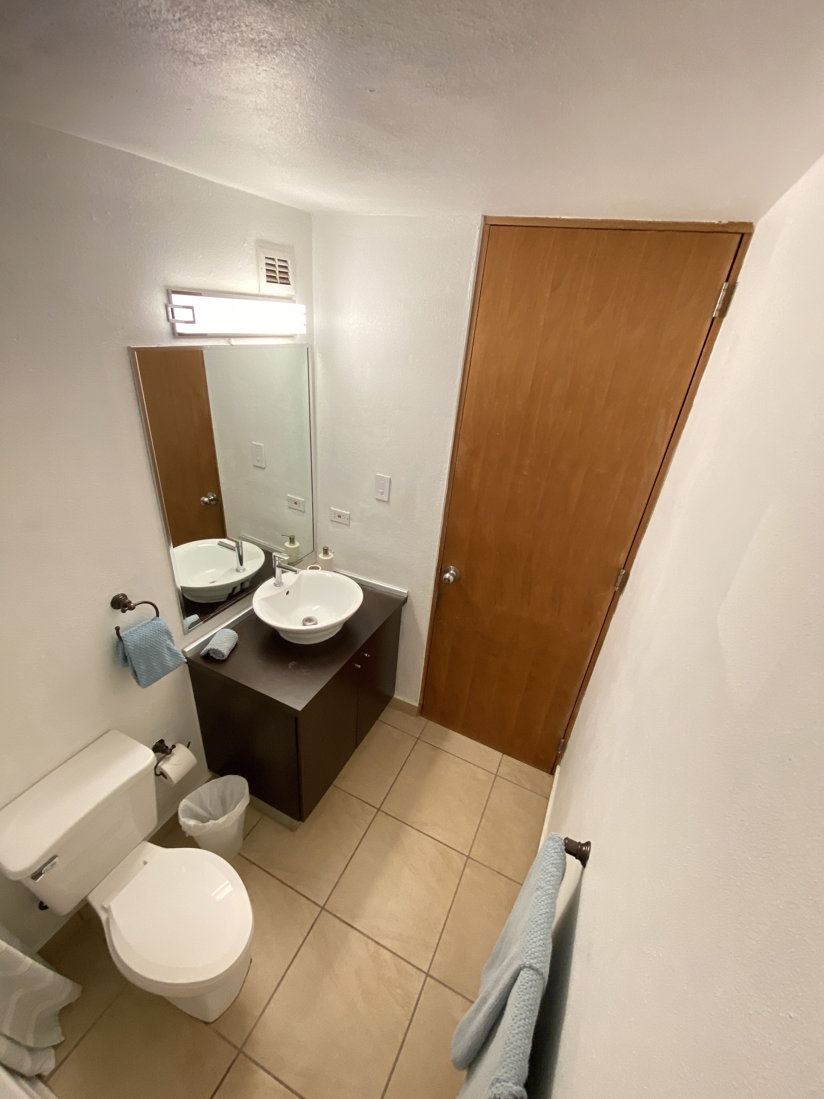 A bathroom with a toilet, sink, and mirror.