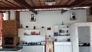 A kitchen with a brick oven, white cabinets, and a tiled backsplash. - House in farmhouse with all structure of leisure and comfort (Mosqueiro (Condomínio Morada do Rio))