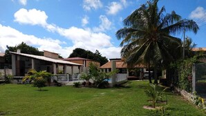 A residential area with houses, a well-maintained lawn, and a palm tree. - House in farmhouse with all structure of leisure and comfort (Mosqueiro (Condomínio Morada do Rio))