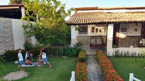 A courtyard with a stone pathway, a white fence, and a building with a tiled roof. - House in farmhouse with all structure of leisure and comfort (Mosqueiro (Condomínio Morada do Rio))