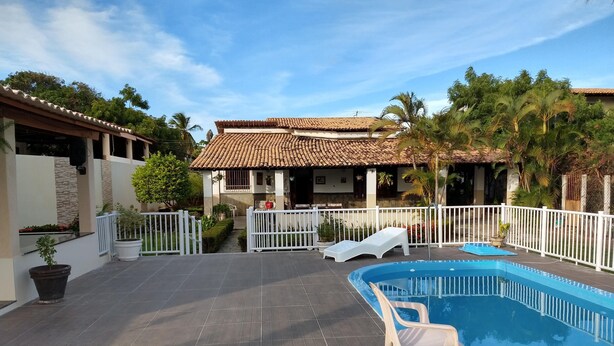 A swimming pool with a white fence, a white chair, and a small white lounge chair. - House in farmhouse with all structure of leisure and comfort (Mosqueiro (Condomínio Morada do Rio))