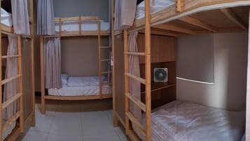 A bunk bed room with curtains, a ladder, and two fans.