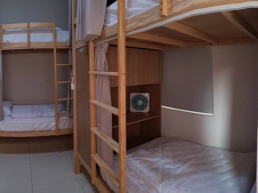 A bunk bed room with curtains, a ladder, and two fans.