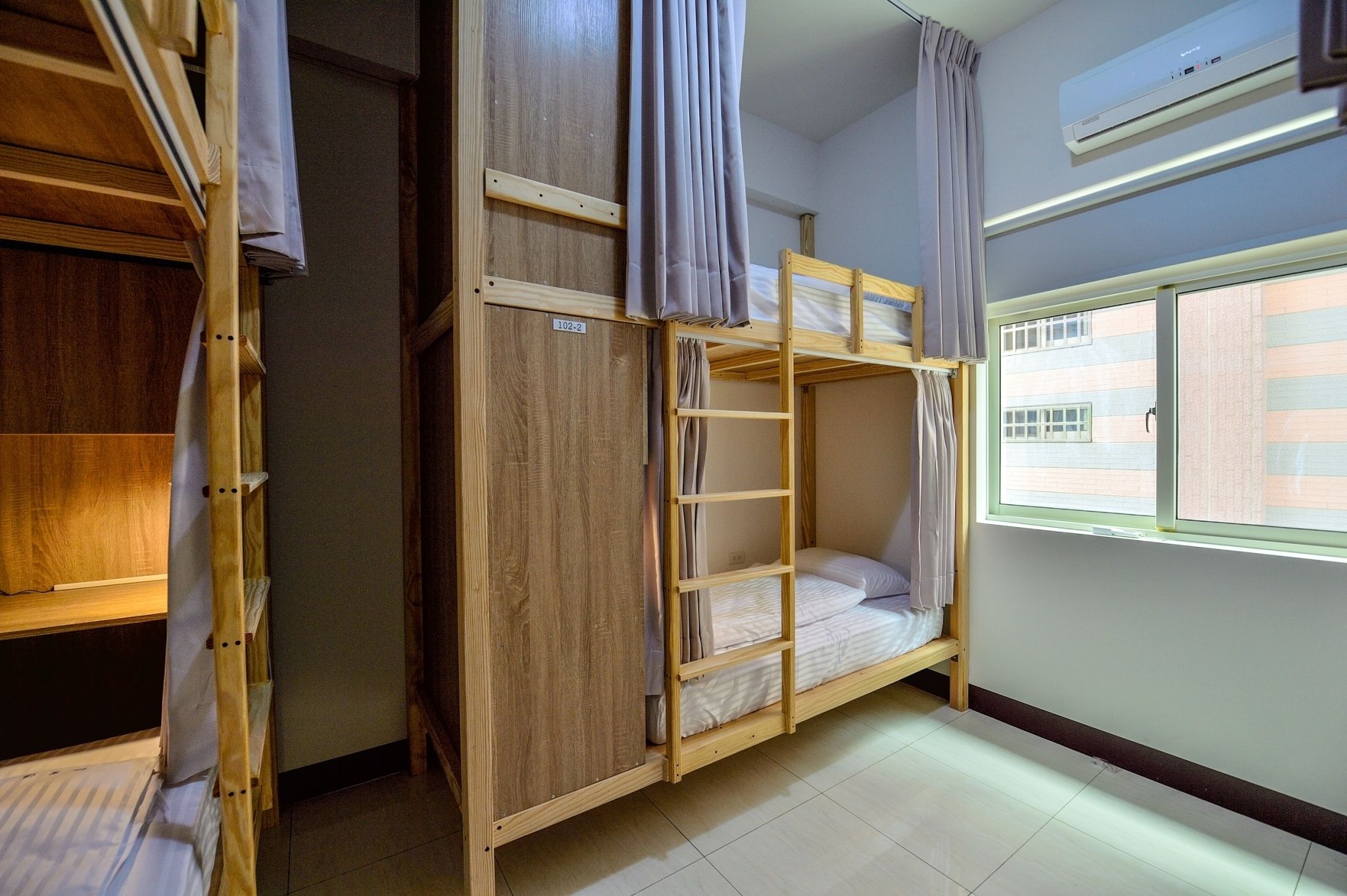 Una habitación con literas, un armario y una ventana con persianas.