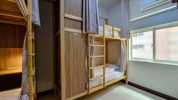 Una habitación con literas, un armario y una ventana con persianas.