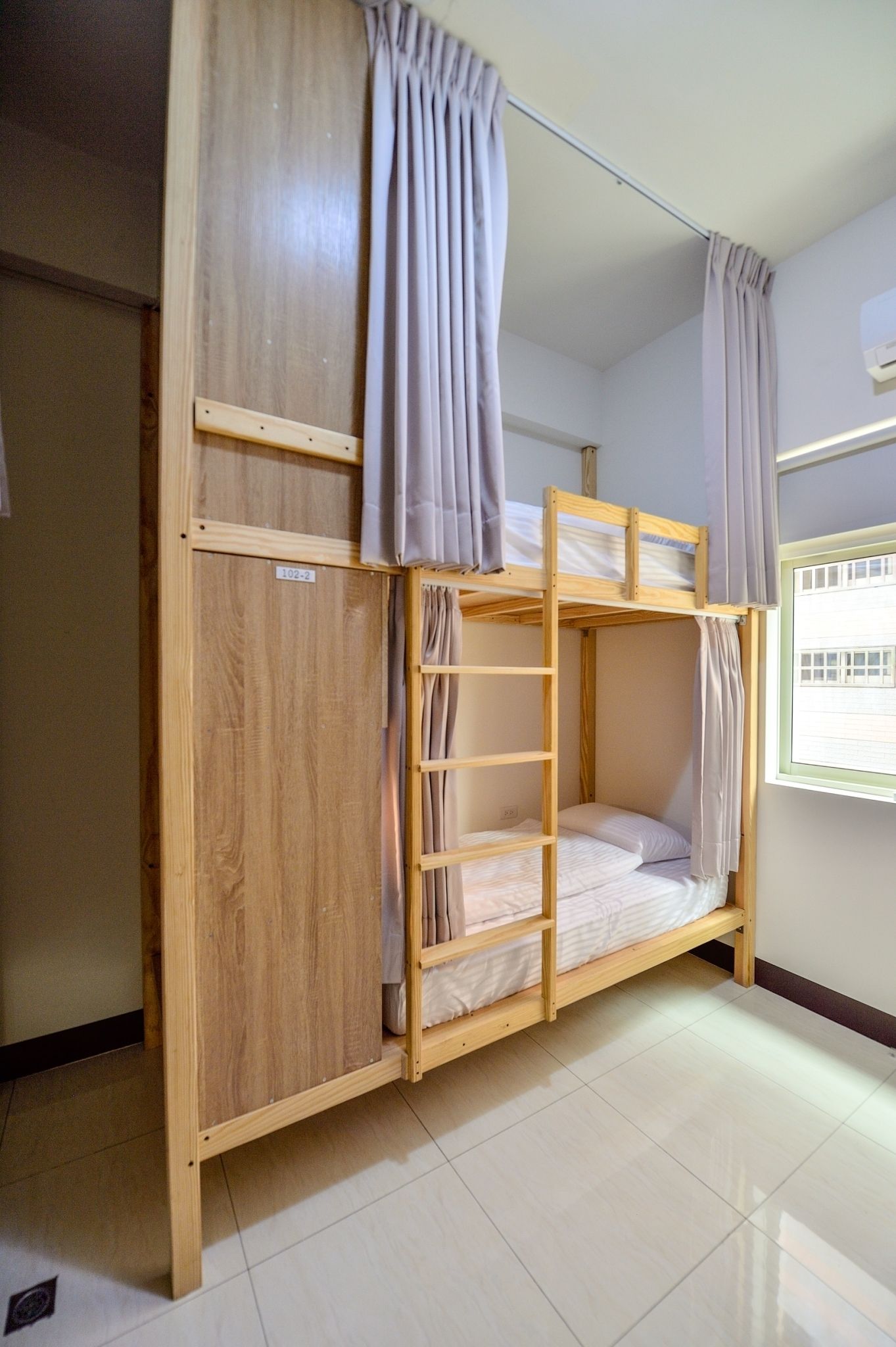 A bunk bed with a wooden frame, a ladder, and curtains.