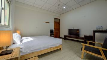 Une chambre d’hôtel avec un lit, une télévision, un bureau et une chaise.