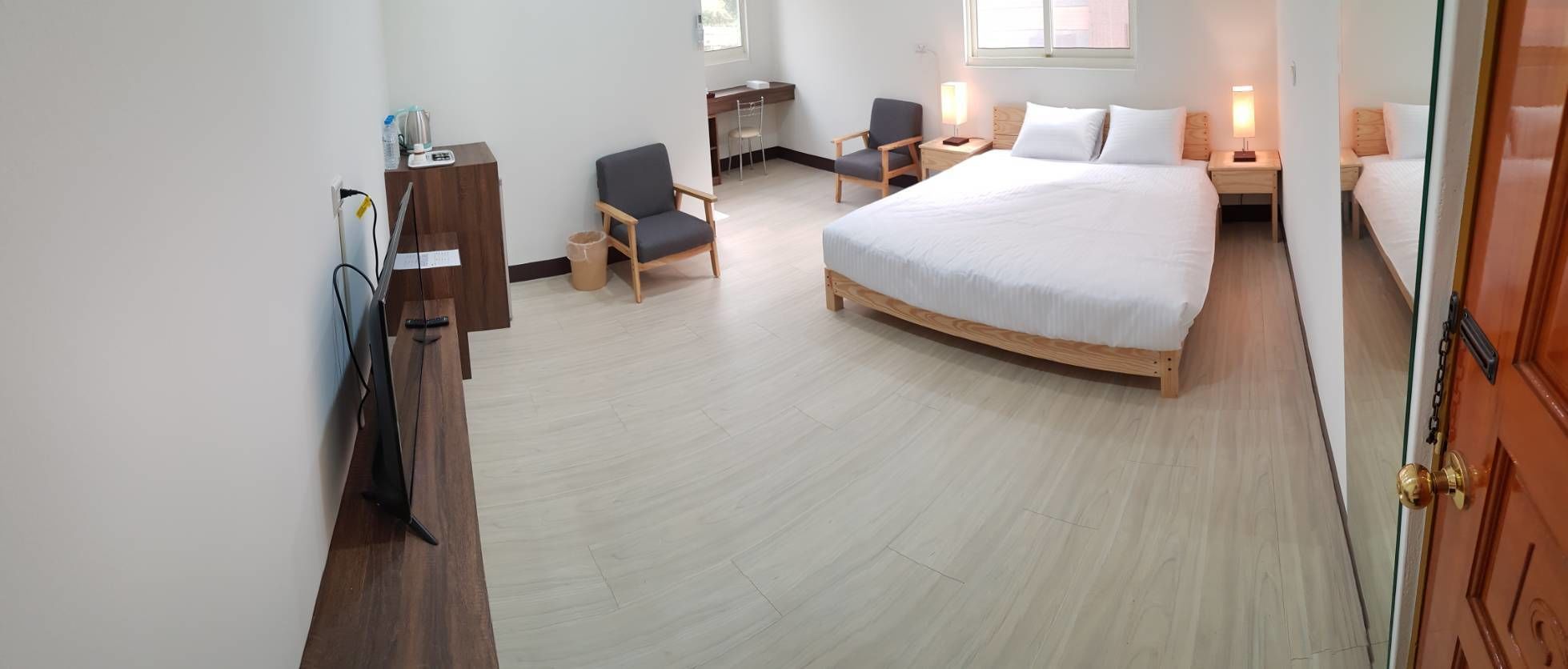 A bedroom with a bed, a desk, a chair, and a TV.