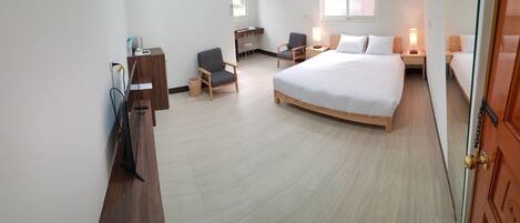 A bedroom with a bed, a desk, a chair, and a TV.