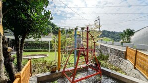 Un élément décoratif aquatique avec une structure rouge, entouré de murs de pierre et de verdure.