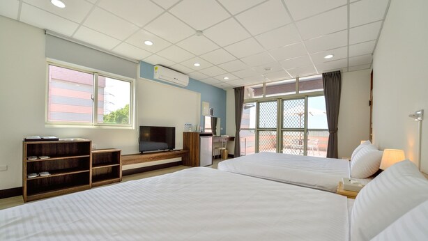 Une chambre d’hôtel avec deux lits, une télévision, un bureau et une fenêtre donnant sur un paysage agréable.