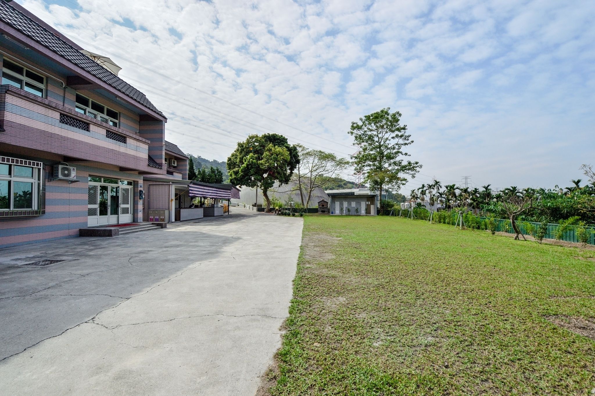 A building with a flat roof, a paved walkway, and a grassy area.