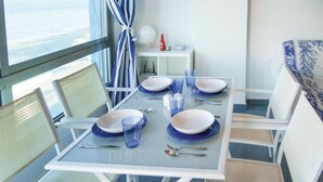 Uma sala de jantar com mesa posta para quatro pessoas, pratos azuis e brancos e copos de vidro.