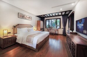 A well-lit bedroom with a large bed, bedside tables, a desk, and a TV. - Maison New Century Nanxun Huzhou (Huzhou)