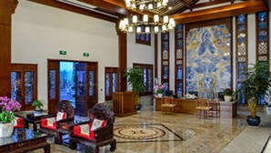 Un hall con muebles de madera tradicionales, una recepción y una planta decorativa grande.