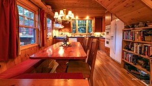 Un intérieur en bois comprenant une table à manger, des chaises, un lustre et une bibliothèque.