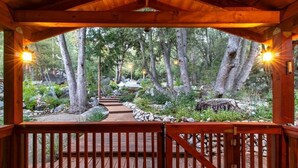 Une terrasse en bois offrant une vue sur une zone boisée, avec un sentier de pierres qui la traverse.