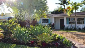 A residential house with a well-maintained garden featuring various plants and a brick pathway.