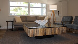 A living room with a glass coffee table, a sofa, a chair, and a lamp.