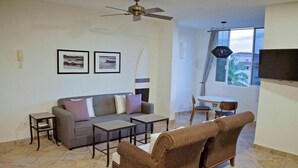 A living room with a grey sofa, two brown wicker chairs, a coffee table, and a TV mounted on the wall. - "Ola",  One bedroom. You can walk to Beach and Restaurants (Punta de Mita)