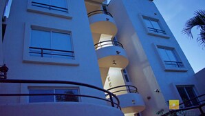 A multi-story building with balconies, large windows, and a palm tree visible in the background. - "Ola",  One bedroom. You can walk to Beach and Restaurants (Punta de Mita)