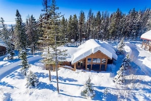 A wooden cabin surrounded by snow-covered trees.