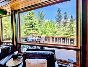 A room with a large window overlooking a deck with outdoor furniture.