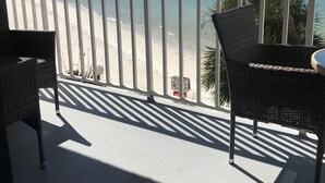 Un balc ón con mobiliario de mimbre con vistas a una playa y un puente.